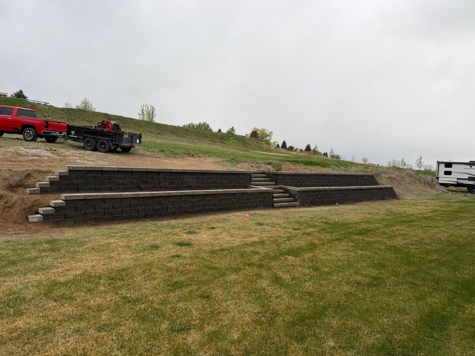 Long terraced block retaining wall with steps on a sloped property